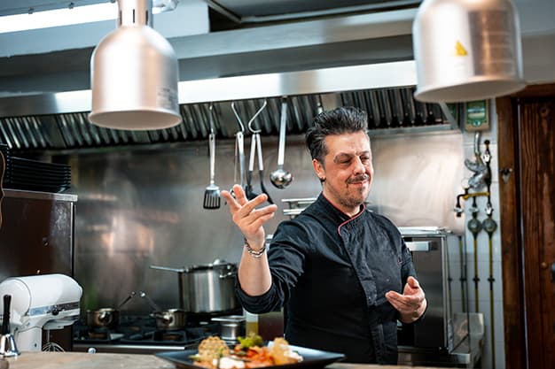 Head chef in the open restaurant kitchen preparing fresh dishes